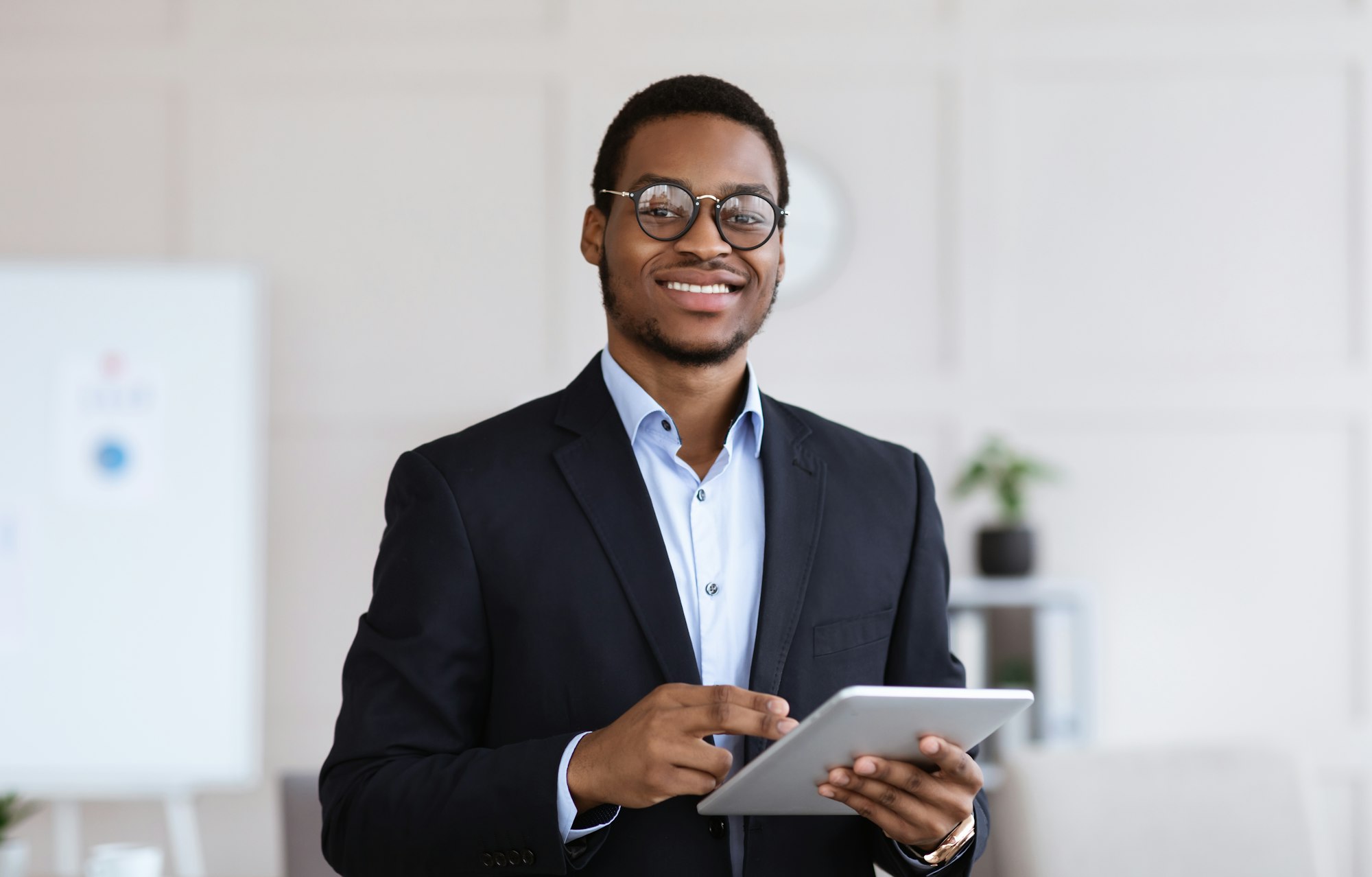 Cheerful black man manager holding digital tablet, office interior