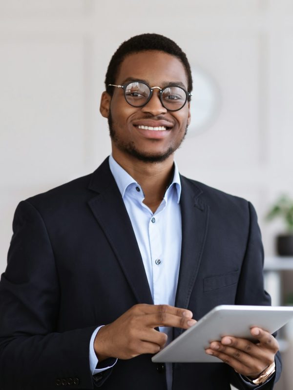 Cheerful black man manager holding digital tablet, office interior