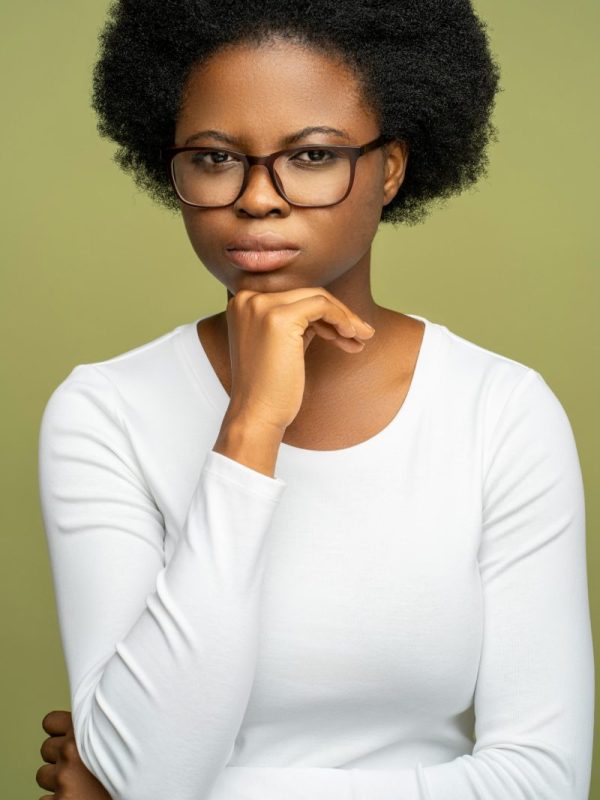 Self assured intelligent African American woman in glasses looking at camera with strict glance.